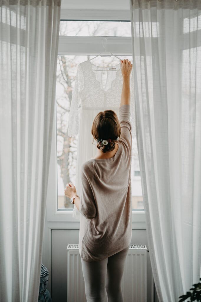 Frau steht im Morgenlicht am Fenster