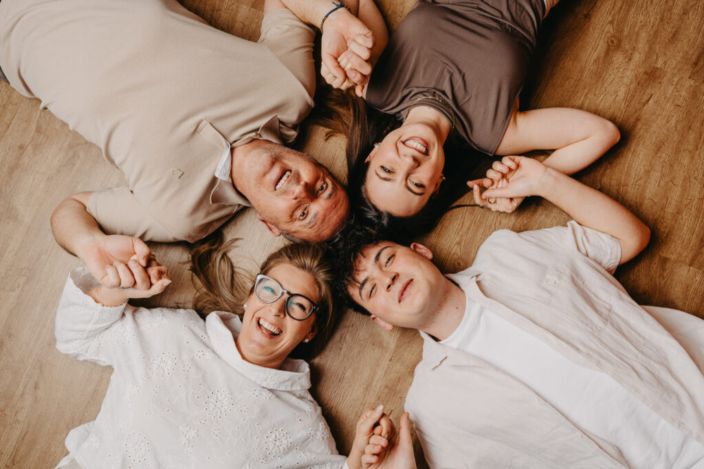 Familie mit zwei Kindern liegt lachend zusammen