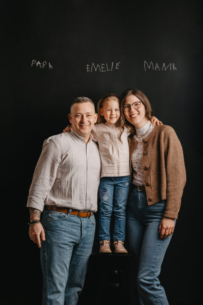 Familie mit Tochter vor schwarzem Hintergrund im Fotostudio